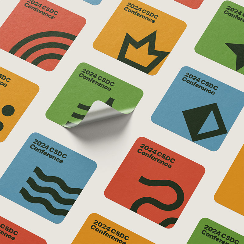 A set of stickers laid out in an angle grid against a gray background. The stickers feature the colorful graphics from the brand identity.