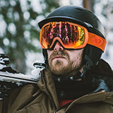 A photo of Gavin, one of the personas for Powder. Gavin is a male who looks to be in his twenties-to-thirties, with facial hair and orange ski goggles on his head.